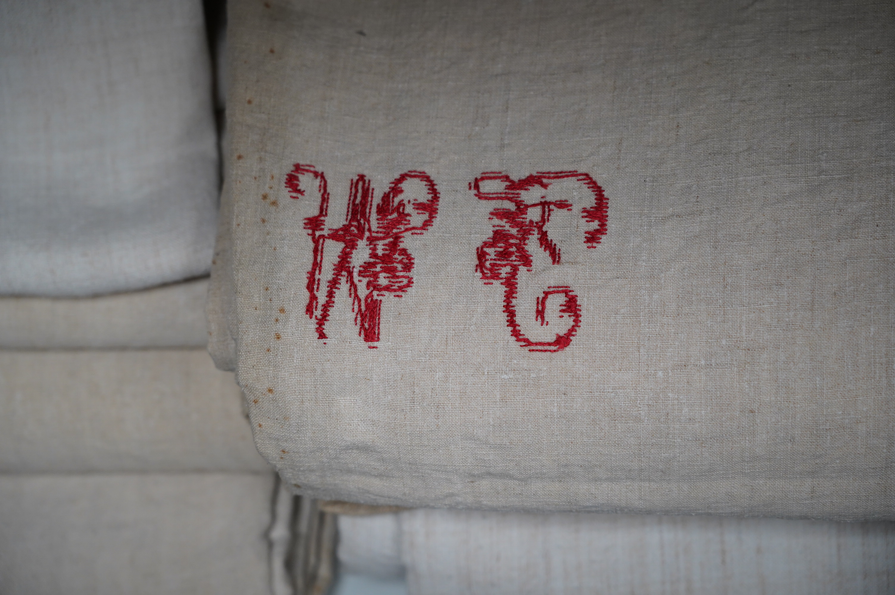 Fourteen French provincial coarse linen sheets, mostly with red embroidered monograms